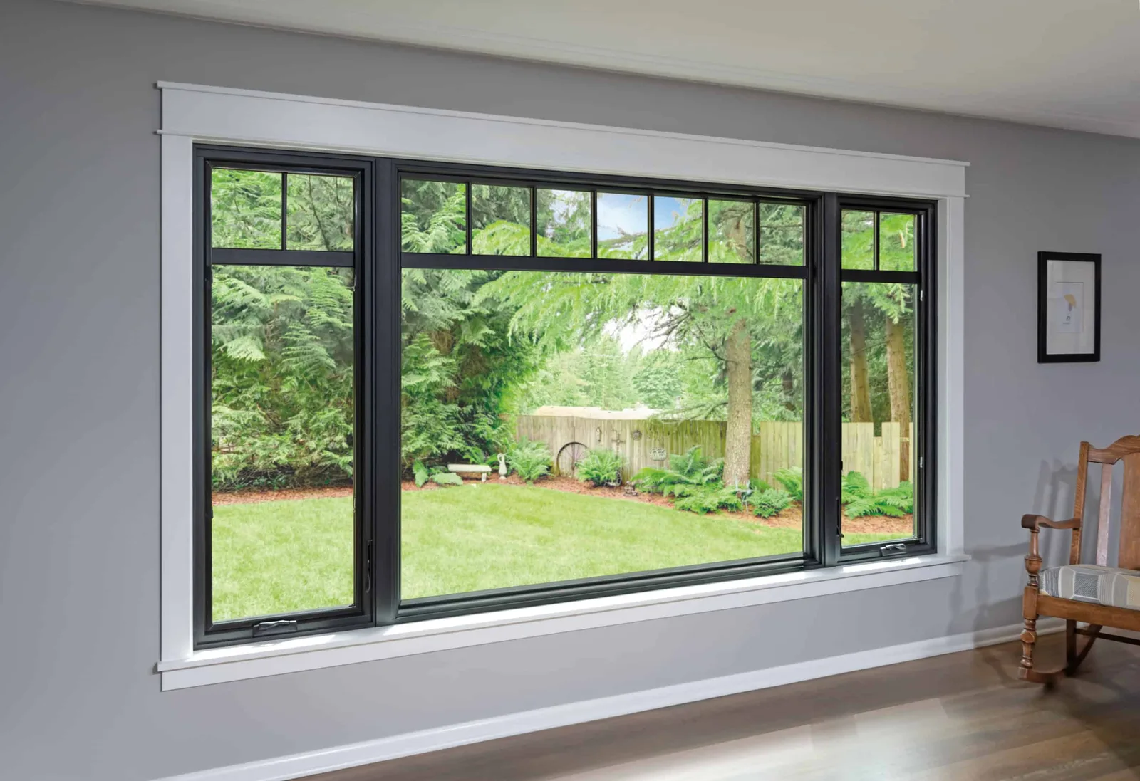 Black-framed replacement windows overlooking a green backyard