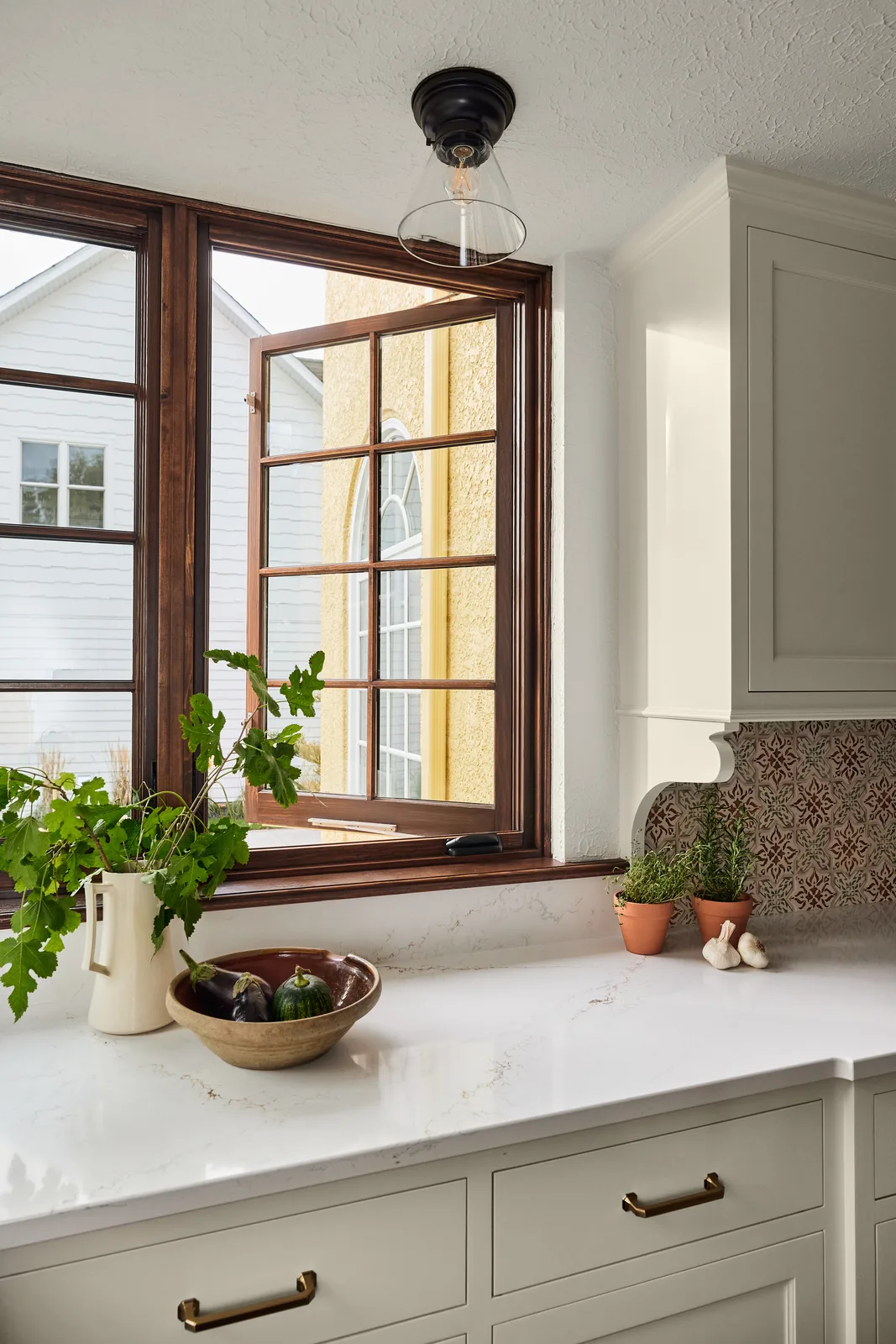 Wood-framed kitchen window with a bright outdoor view